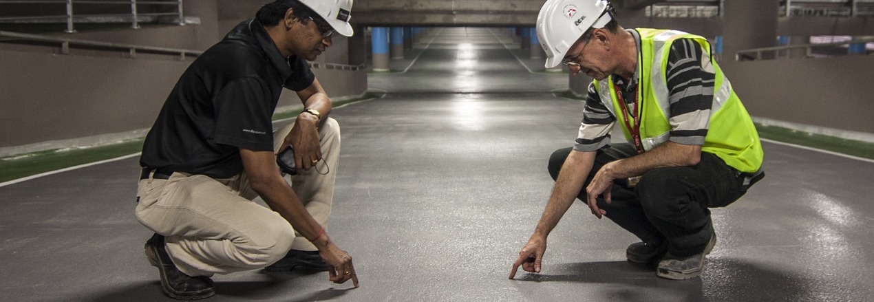 Two men wearing PPE pointing at the floor.